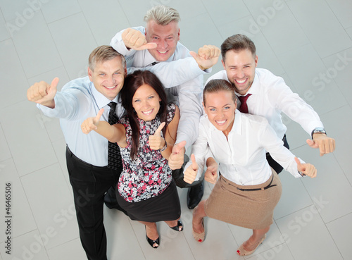 Photo: Successful young business people showing thumbs up sign Successful young business people showing thumbs up sign