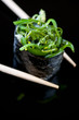 Vertical shot of chopsticks holding sushi with chuka salad