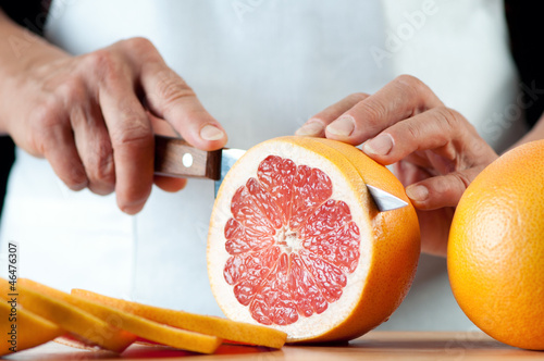 Photo: Senior woman slicing a grapefruit, horizontal shot Senior woman slicing a grapefruit, horizontal shot