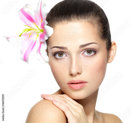 Photo: Beauty face of young woman with flower. Beauty treatment concept Beauty face of young woman with flower. Beauty treatment concept
