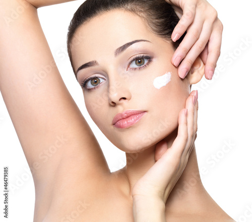 Photo: Beauty face of young woman with cosmetic cream on a cheek. Beauty face of young woman with cosmetic cream on a cheek.