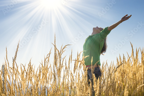 Photo: Happy young girl raising her arms with bliss and joy Happy young girl raising her arms with bliss and joy