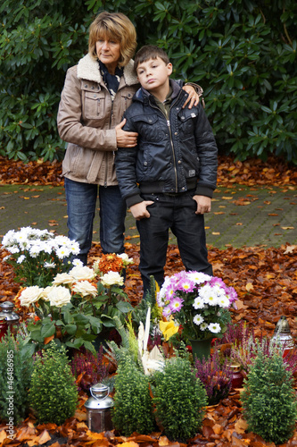 Photo: Mutter und Kind stehen an einem Grab Mutter und Kind stehen an einem Grab