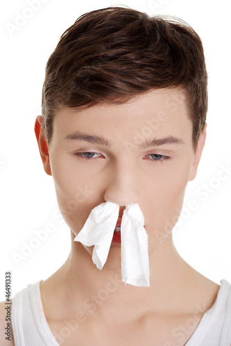 Photo: Sick man with a cold with tissue in his nose Sick man with a cold with tissue in his nose