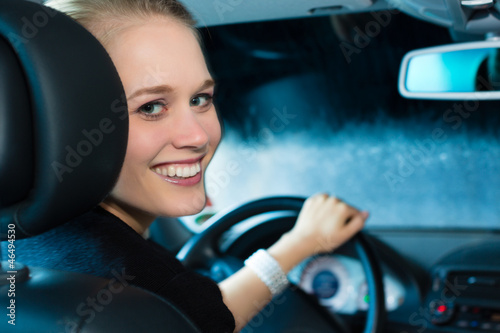 Photo: Young woman drives car in wash station Young woman drives car in wash station