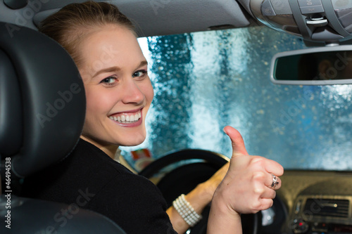 Photo: Young woman drives car in wash station Young woman drives car in wash station