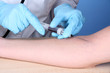 Nurse takes blood from the veins on blue background