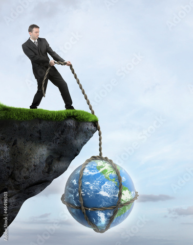 Photo: Businessman saving Earth from falling of the cliff Businessman saving Earth from falling of the cliff