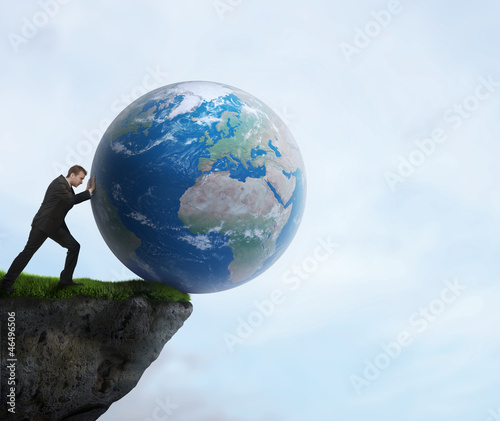 Photo: Businessman pushing planet Earth off the cliff Businessman pushing planet Earth off the cliff
