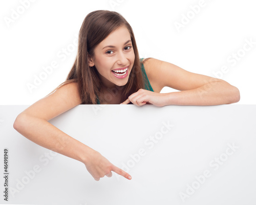 Photo: Young woman pointing at blank poster Young woman pointing at blank poster