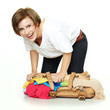 Happy young woman packs her overcrowded bag for holidays