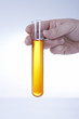 Hand holding test tube with yellow liquid