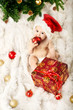 Christmas baby  sitting on fur and eating gift