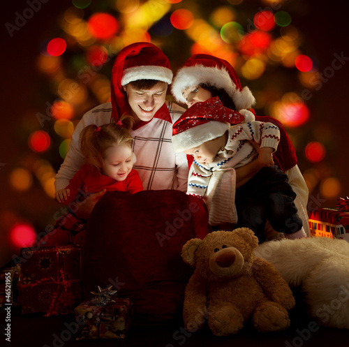 Photo: Christmas family opening lighting bag with gifts Christmas family opening lighting bag with gifts