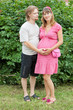 a happy young pregnant woman with her husband rests in a park