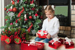 Happy little girl open a red gift box near christmas tree