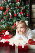 Pretty girl with gift dreaming near christmas tree