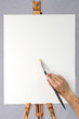 Artist holding brush on blank canvas ready for customizarion