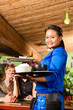 Young people with waitress eating in Thai restaurant