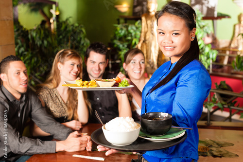 Photo: Young people with waitress eating in Thai restaurant Young people with waitress eating in Thai restaurant