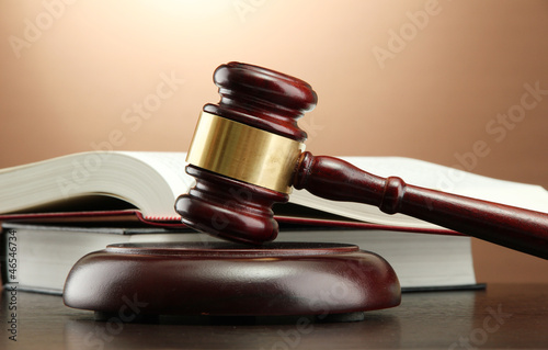 Photo: wooden gavel and books on wooden table,on brown background wooden gavel and books on wooden table,on brown background