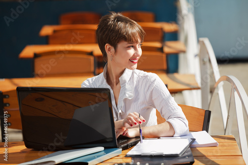 Photo: Young businesswoman with laptop at a sidewalk cafe Young businesswoman with laptop at a sidewalk cafe