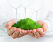 Photo: Male hands holding a green hill with wind turbines Male hands holding a green hill with wind turbines
