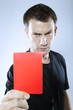 Portrait of a serious referee showing a red penalty card
