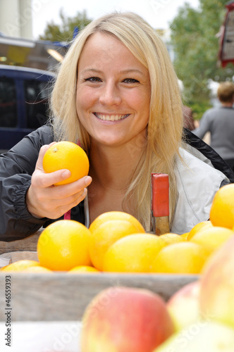 Photo: Junge Frau kauft Orangen auf Markt Junge Frau kauft Orangen auf Markt