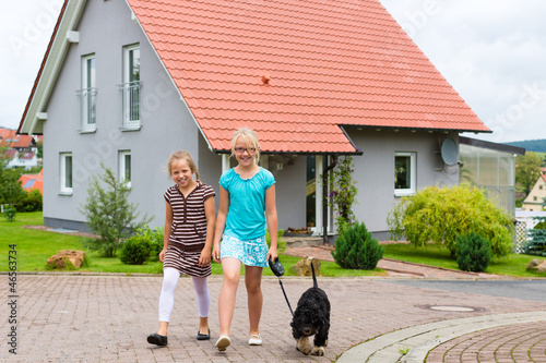 Photo: Two girl or children walking with dog Two girl or children walking with dog