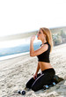 Woman drinking water on the beach after a workout