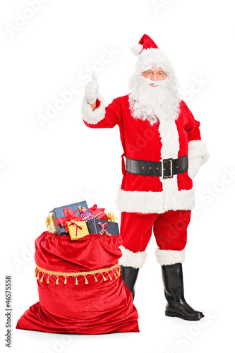 Photo: Santa Claus with a bag full of gifts giving a thumb up Santa Claus with a bag full of gifts giving a thumb up