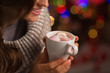Closeup on hot chocolate with marshmallows in hand of woman