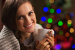 Happy woman enjoying cup of hot chocolate near Christmas tree