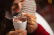 Closeup on woman taking out marshmallow from cup of chocolate