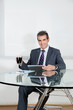 Businessman With Coffee Cup Using Digital Tablet In Office
