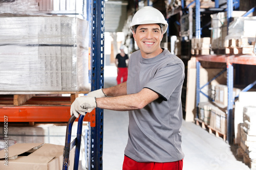 Photo: Warehouse Worker Pushing Handtruck With Cardboard Boxes Warehouse Worker Pushing Handtruck With Cardboard Boxes