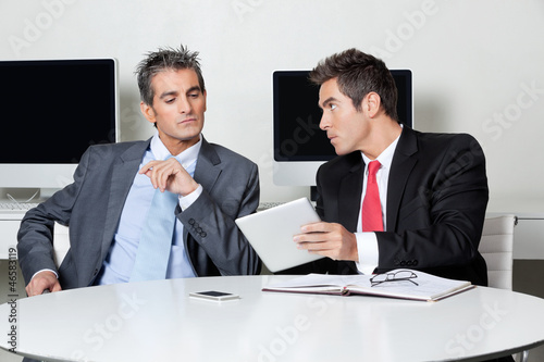 Photo: Businessmen Using Digital Tablet At Desk Businessmen Using Digital Tablet At Desk