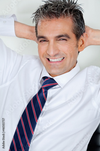 Photo: Mid Adult Businessman Relaxing With Hands Behind Head Mid Adult Businessman Relaxing With Hands Behind Head