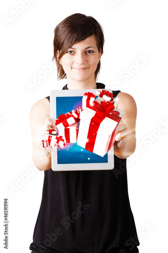 Photo: Young woman looking at modern tablet with present boxes Young woman looking at modern tablet with present boxes