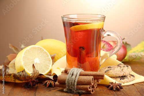 Photo: cup of hot tea and autumn leaves, on brown background cup of hot tea and autumn leaves, on brown background