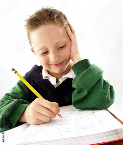 Photo: Niño estudiando, escribiendo,sentado en un pupitre.escolar. Niño estudiando, escribiendo,sentado en un pupitre.escolar.