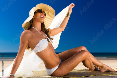 Photo: Attraktive Frau im Bikini lacht die Sonne am Strand an Attraktive Frau im Bikini lacht die Sonne am Strand an