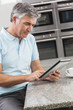 Man Using Tablet Computer in Kitchen Drinking Coffee
