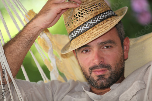 Photo: Man relaxing in hammock whilst on holiday Man relaxing in hammock whilst on holiday
