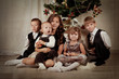 Five children are sitting around the Christmas tree