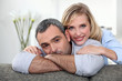 A nice couple cuddling on a couch.
