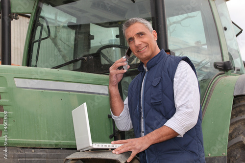 Photo: farmer near a tractor with computer farmer near a tractor with computer
