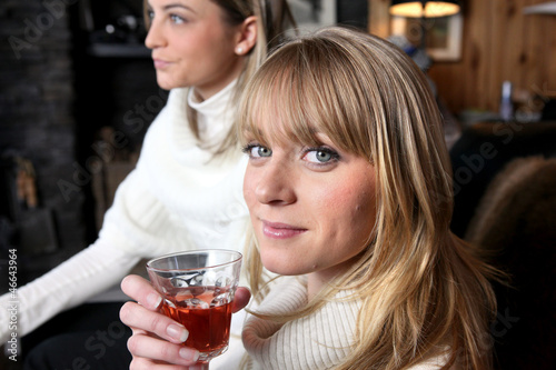 Photo: Two female friends relaxing at home with glass of wine Two female friends relaxing at home with glass of wine