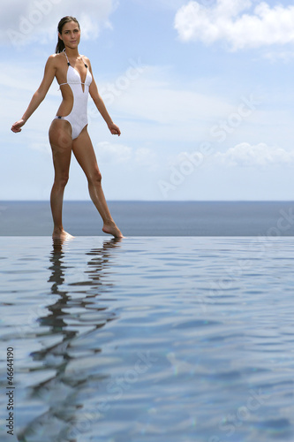Photo: Woman stood by infinity pool Woman stood by infinity pool